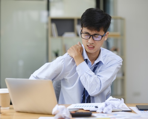 exhausted businessman suffering shoulders pain from work