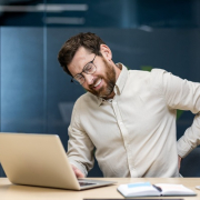 man with lower back pain desk