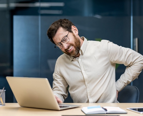 man with lower back pain desk