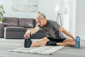 Man stretching on exercise mat indoors.