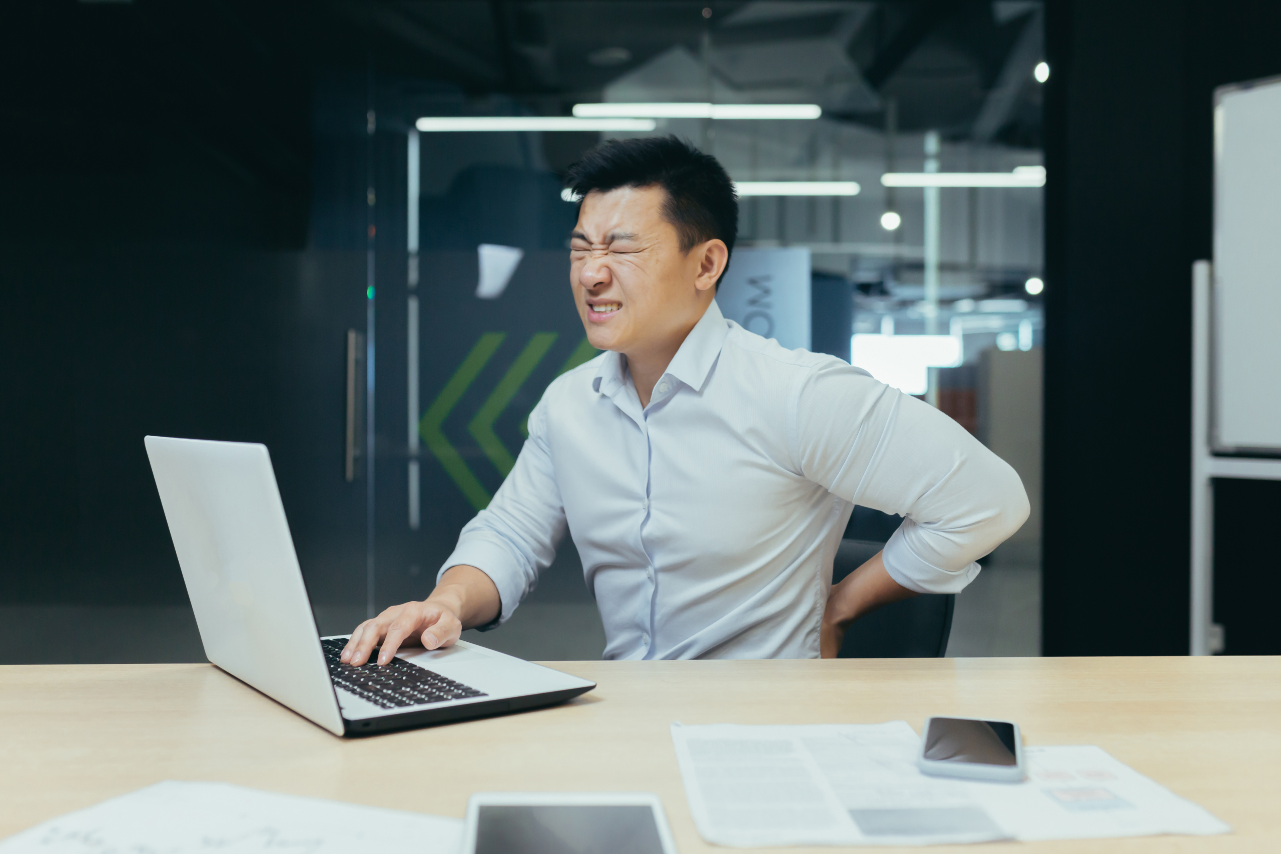 asian businessman working in office having lower back ache symptoms