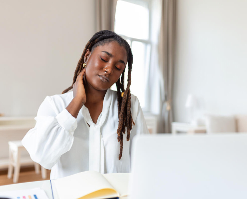 businesswoman experiencing back of neck aches after sitting at desk