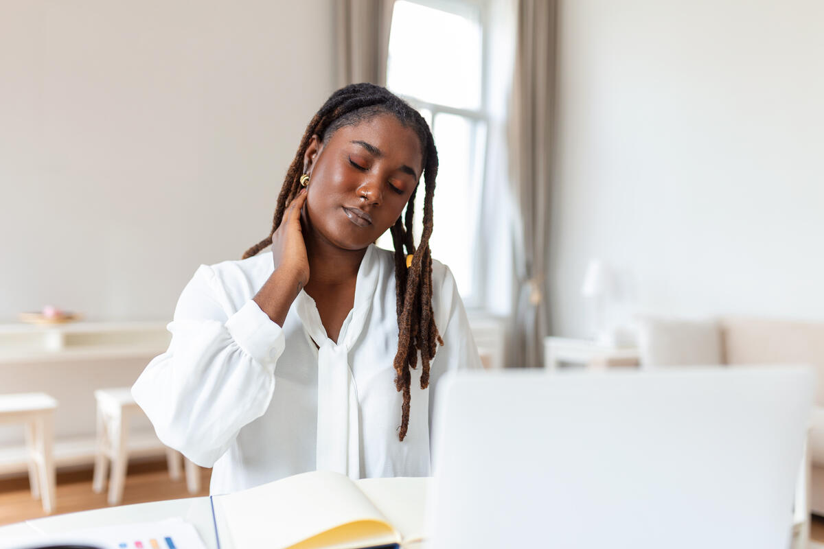 businesswoman experiencing back of neck aches after sitting at desk