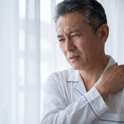 Person holding painful shoulder in need of frozen shoulder treatment
