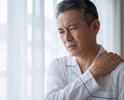 Person holding painful shoulder in need of frozen shoulder treatment