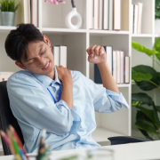Asian man at office desk suffering from shoulder pain and muscle strain in need of muscle healing support