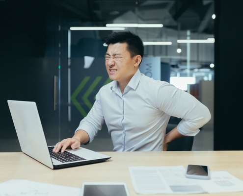 asian businessman working in office having lower back ache symptoms