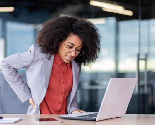 Office worker experiencing lower back pain from lack of ergonomic support at desk