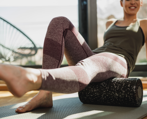 Person using a foam roller for tight hips on an exercise mat at home