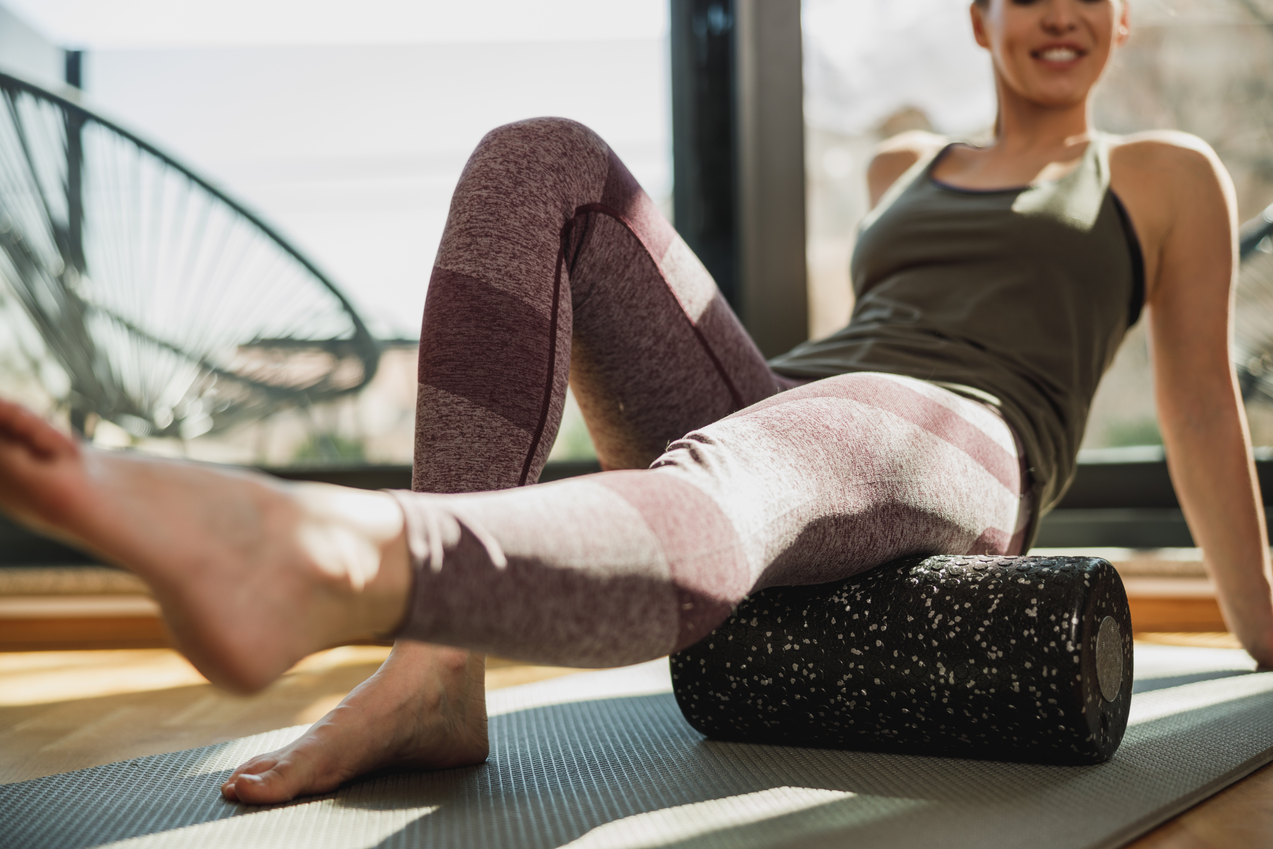 Person using a foam roller for tight hips on an exercise mat at home