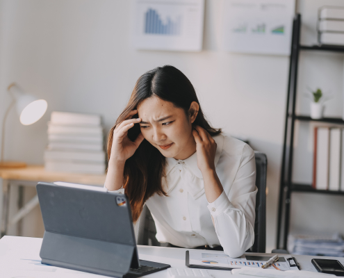woman experiencing neck and head pain while working at a desk