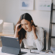 woman experiencing neck and head pain while working at a desk