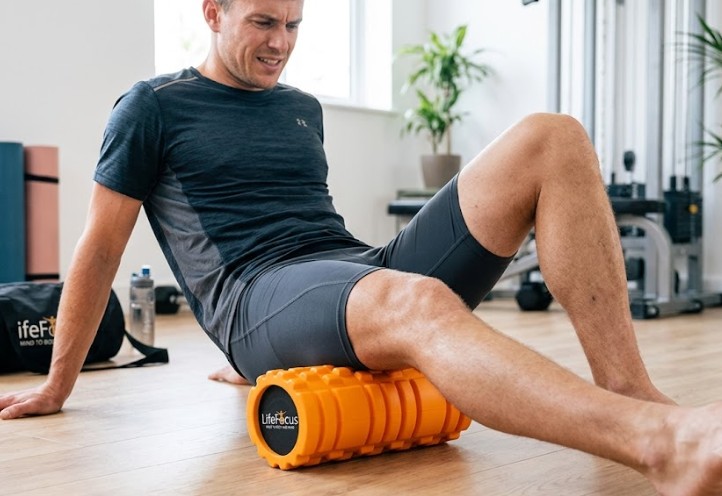 Person using a recovery foam roller on tight hamstrings