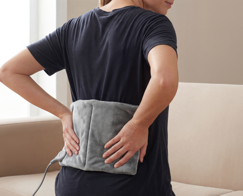 Person applying a hot cold pack for lower back pain