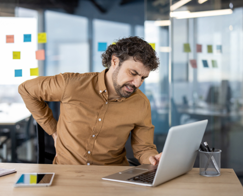 man experiencing muscle knots in back after long hours at office desk