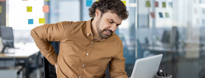 man experiencing muscle knots in back after long hours at office desk