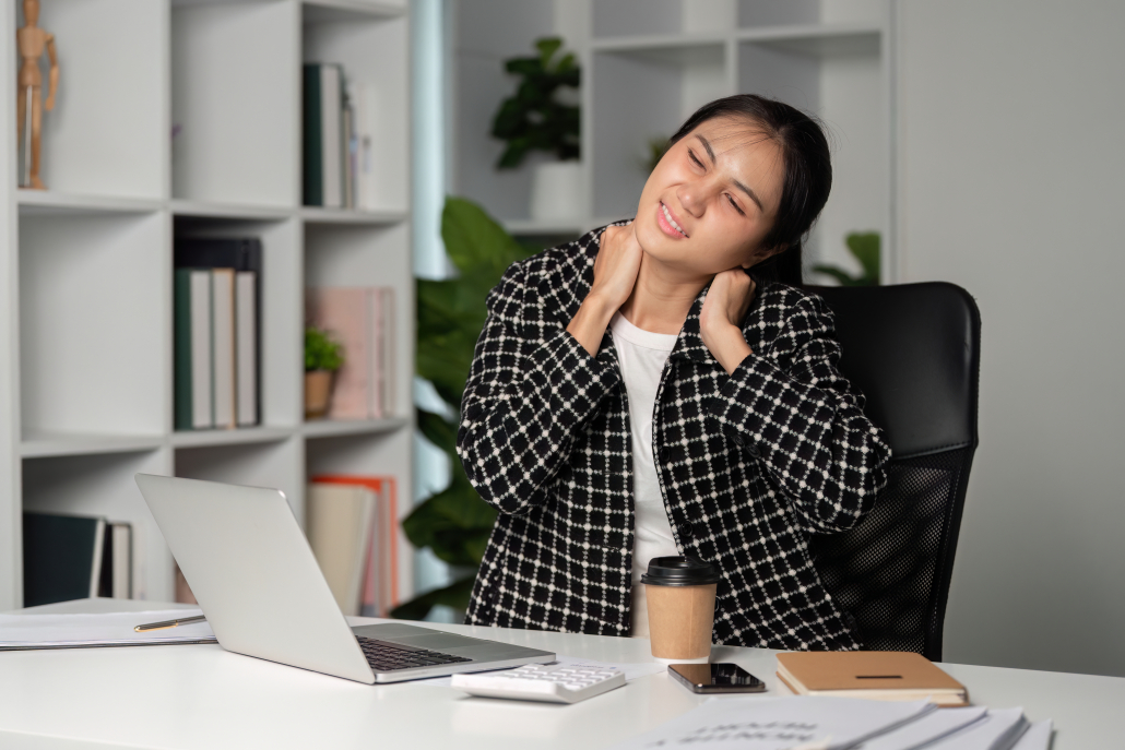 woman stretching neck desk Desk worker rubbing a sore neck before trying a neck stretcher device