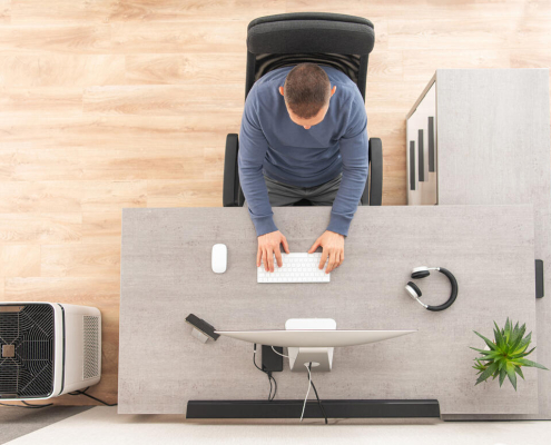 man using cold pack for back pain relief at home office desk
